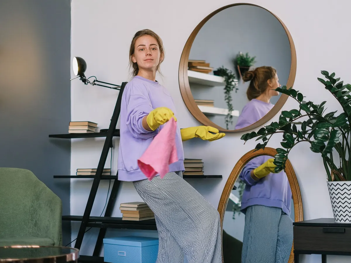 Woman cleaning a mirror in a bright home