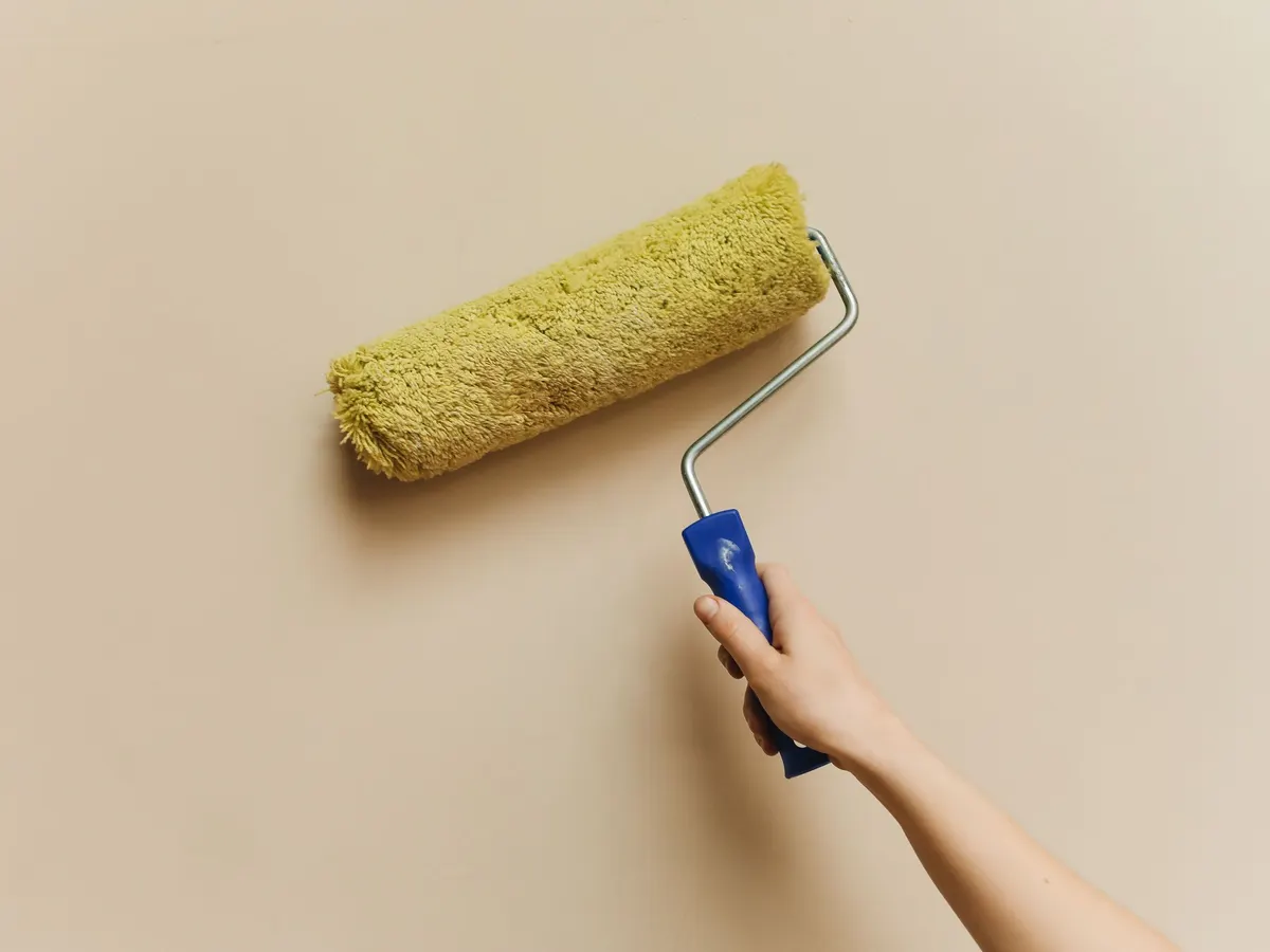 Paint roller painting a beige wall