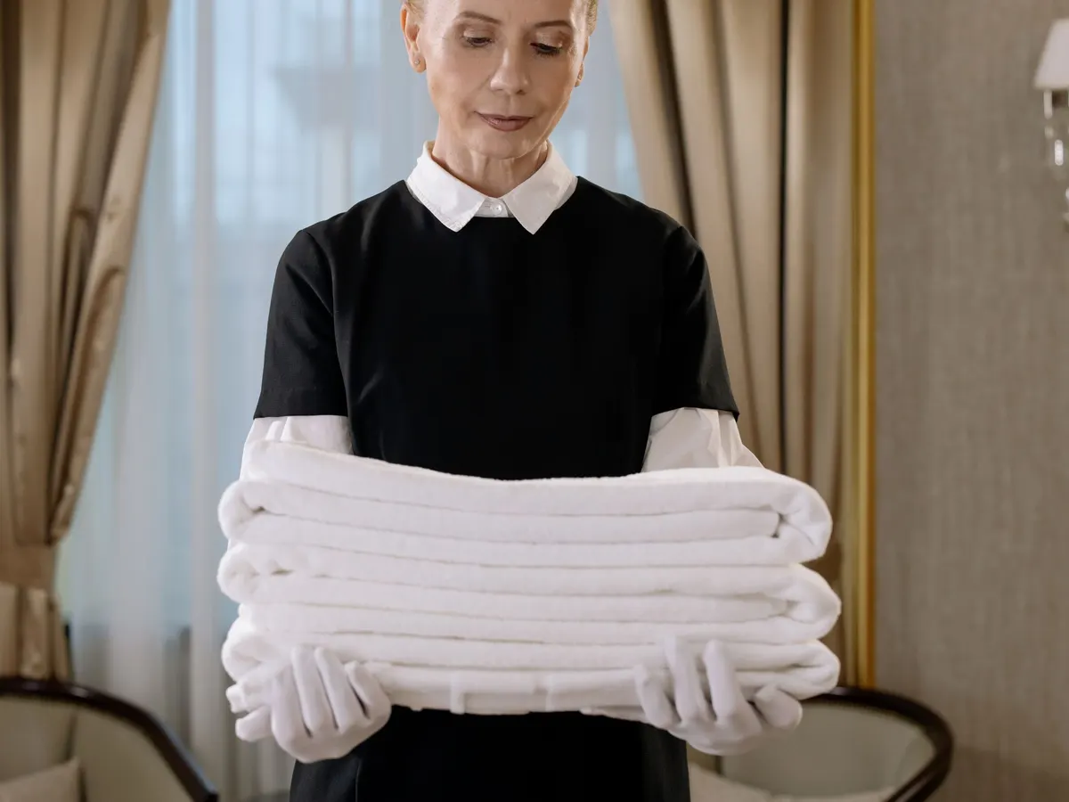 Housekeeper in uniform holding folded towels